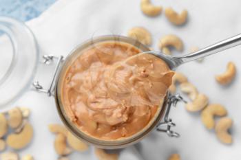 Spoon and jar of cashew butter on table, closeup�