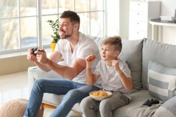 Father and his little son playing video games at home�