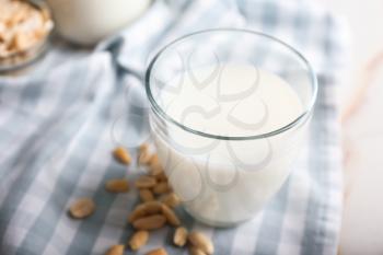 Glass of tasty peanut milk on white table�