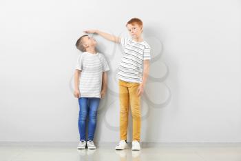 Cute little boys measuring height near light wall�