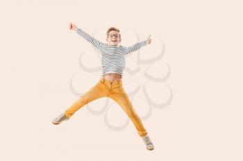 Jumping little boy showing thumb-up gesture on light background�