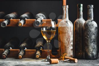 Bottles and glass of wine on table in cellar�
