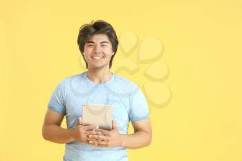 Male Asian programmer with tablet computer on color background�