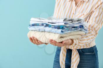 Young woman with clean laundry on color background�