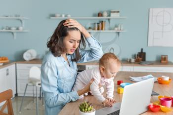 Stressed mother with her baby working at home�