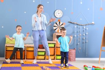 Nanny and cute little children dancing at home�