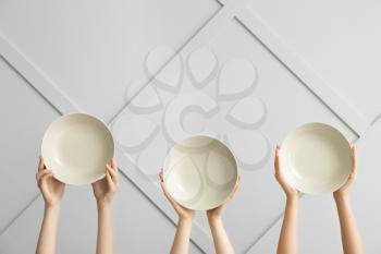 Hands with clean plates on light background�