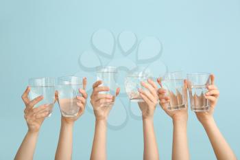 Female hands with glasses of water on color background�