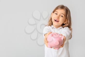 Cute girl with piggy bank on white background�