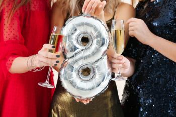 Beautiful young women with champagne and balloon in shape of figure 8. International Women's Day celebration�