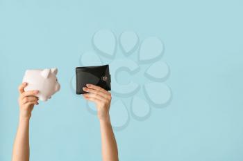 Female hands with piggy bank and wallet on color background�