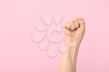 Hand of woman with clenched fist on color background�