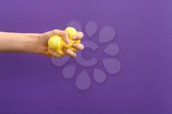 Hand squeezing stress ball on color background�