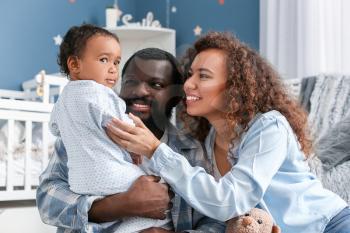 Happy African-American parents with cute baby at home�