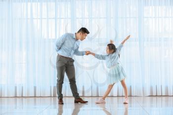 Happy Asian man dancing with his little daughter at home�