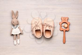 Baby booties with toys on wooden background�