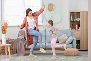 Happy mother and her little daughter dancing at home�