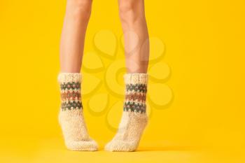 Legs of young woman in warm knitted socks on color background�