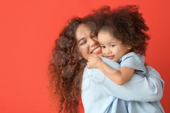 Little African-American girl with her mother on color background�