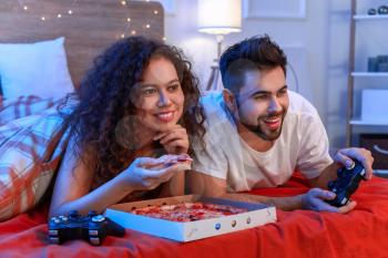 Happy young couple playing video games in bedroom�