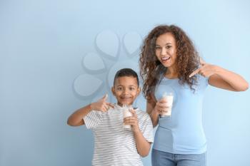 African-American woman and her son with milk on color background�