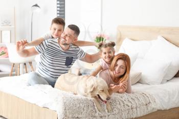 Happy family with dog in bedroom at home�