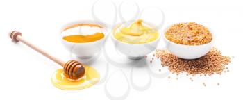 Bowls of honey, mustard and sauce on white background�