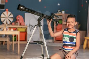 Little African-American boy with telescope looking at stars in evening�