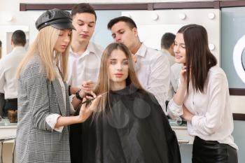 Professional hairdresser teaching young people in salon�