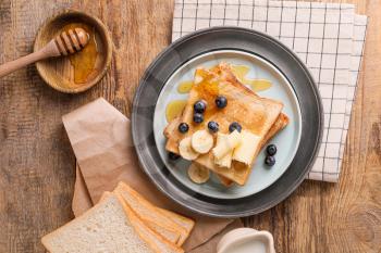 Tasty toasted bread with honey, butter and fruits on plate�