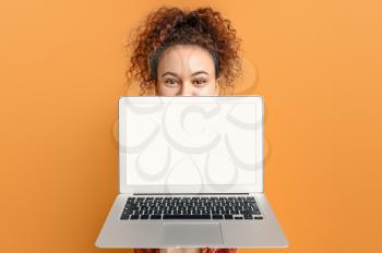 Beautiful young African-American woman with laptop on color background�