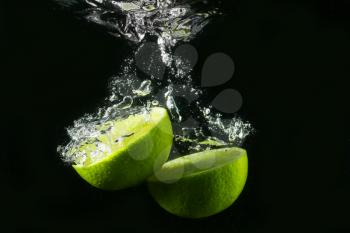 Falling of cut lime into water against dark background�