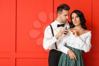 Stylish young couple with perfume on color background�