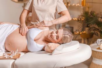 Young pregnant woman having massage in spa salon�
