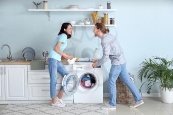 Happy young couple doing laundry at home�