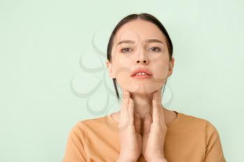 Young woman with thyroid gland problem on color background�