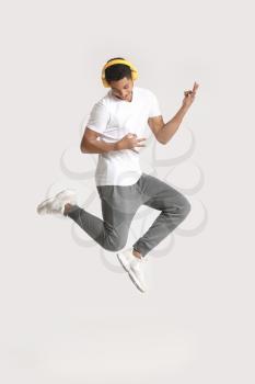 African-American teenager dancing and listening to music against light background�