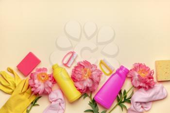 Set of cleaning supplies and spring flowers on color background�