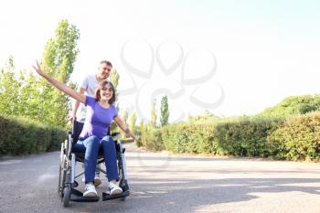 Happy young woman in wheelchair and her husband outdoors�