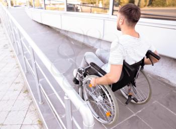 Young man in wheelchair on ramp outdoors�