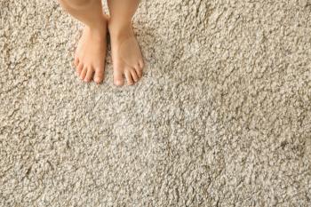 Barefoot girl standing on carpet�