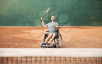 Young man in wheelchair playing tennis on court�