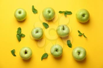 Ripe fresh apples with mint on color background�