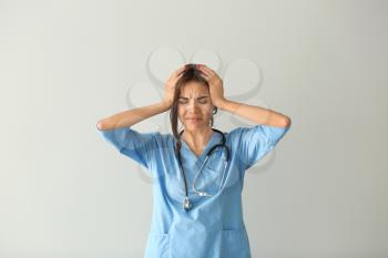 Stressed female nurse on light background�