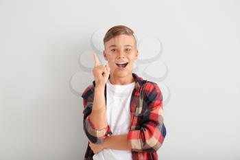 Emotional teenage boy with raised index finger on white background�