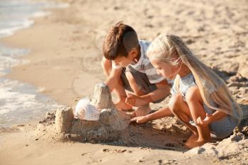 Cute little children building sand castle on sea beach�