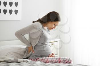 Pregnant woman suffering from pain in bedroom�