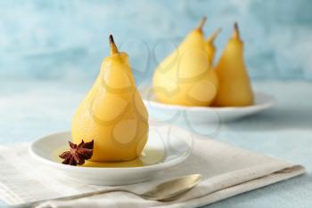 Plate with delicious poached pear in wine on color table�