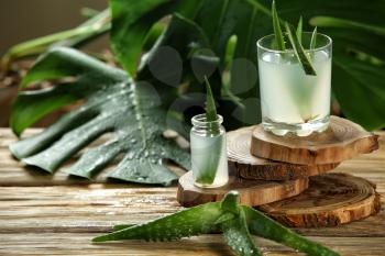 Bottle and glass with fresh aloe vera juice on wooden table�
