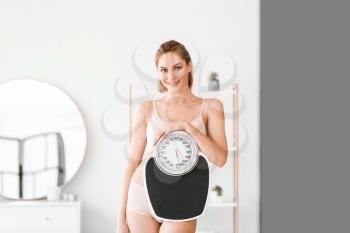 Young woman with weight scales at home�